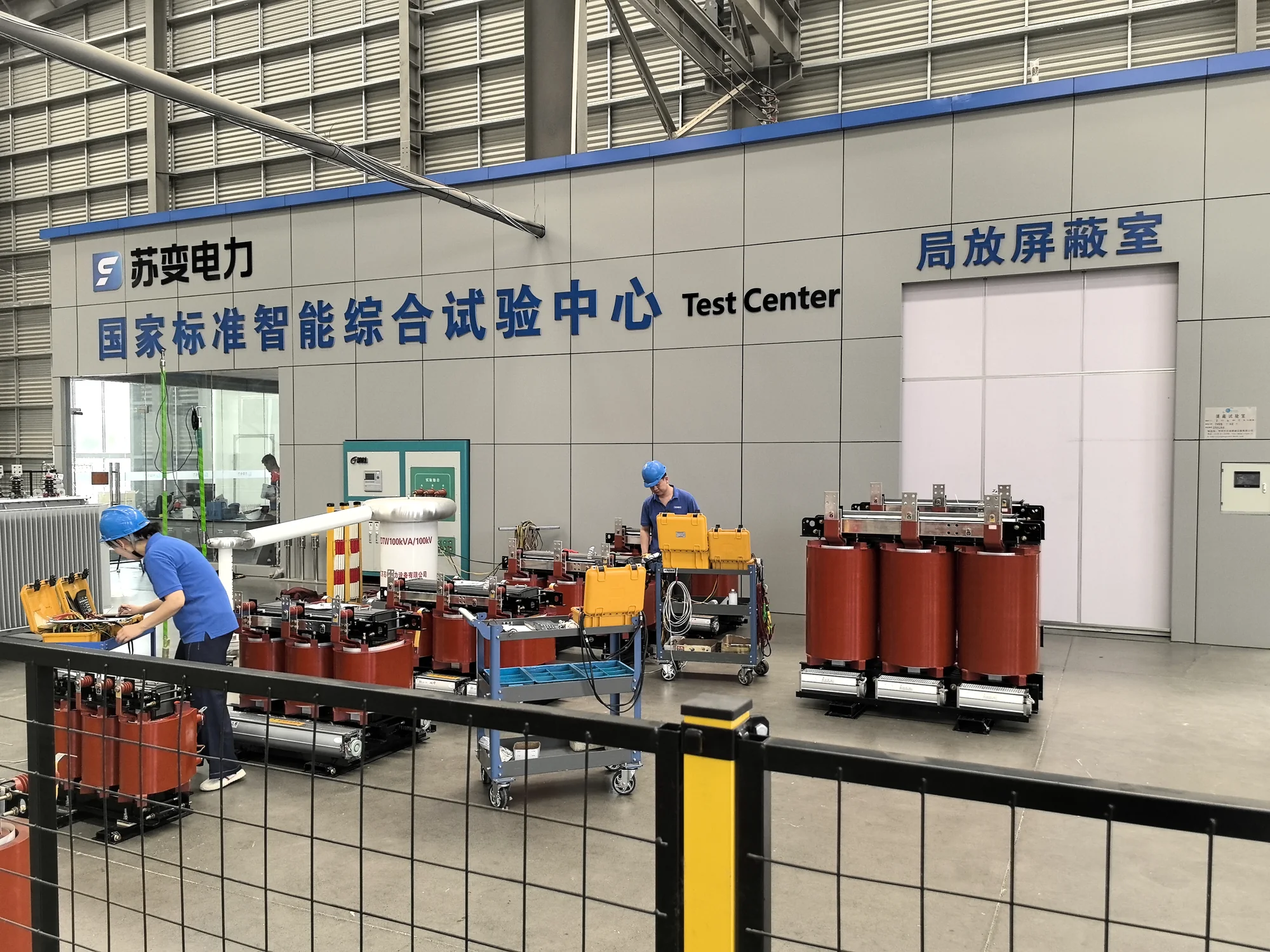 Technicians with dry-type transformers and test equipment in a group test center.